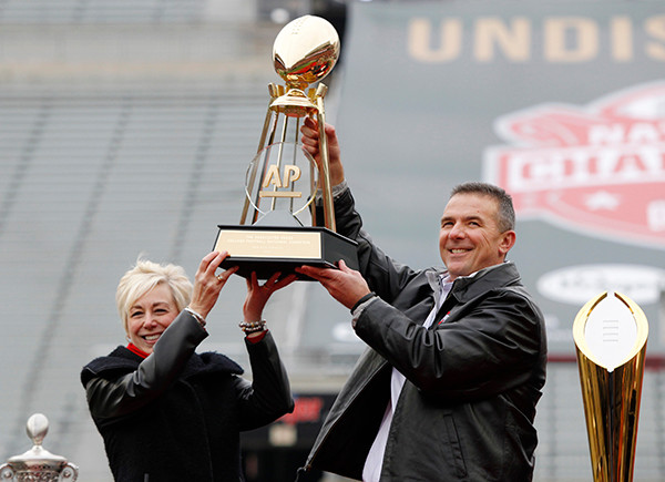 Ohio State coach Urban Meyer, right, and The Associated Press' east regional director Eva Parziale hold up The Associated Press college football national championship trophy during a celebration of the Buckeye's 2014 College Football Playoff national champion  at Ohio Stadium in Columbus, Ohio, Saturday, Jan. 24, 2015. (AP Photo/Paul Vernon)